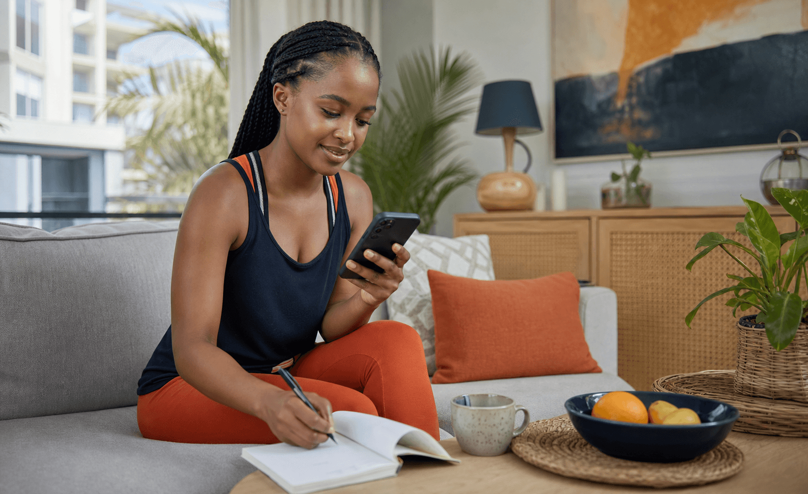 Tanzanian woman reflecting in a journal while using the GENO Wellness app